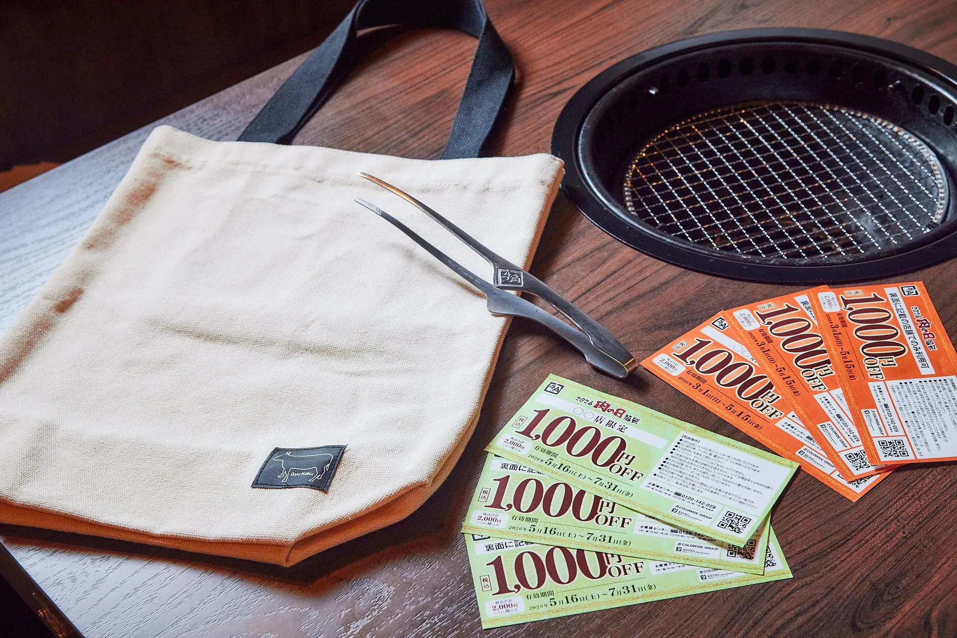 焼肉店のノベルティグッズの写真。トートバッグ、トング、焼肉グリル、割引券が写っている。